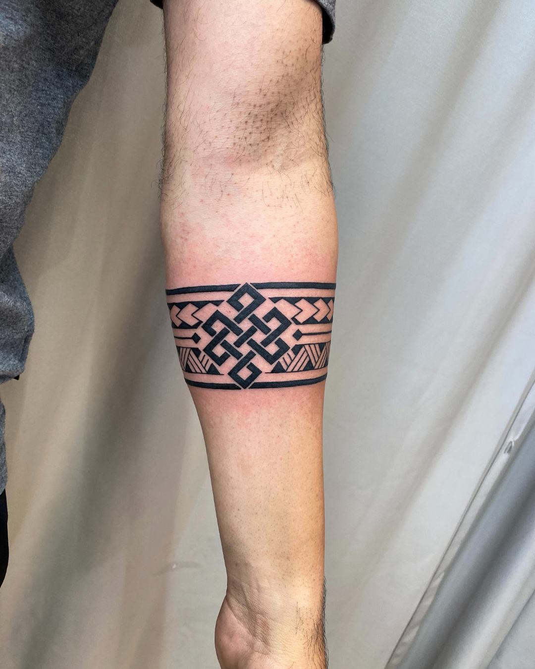 Solid black geometric armband tattoo with tribal elements