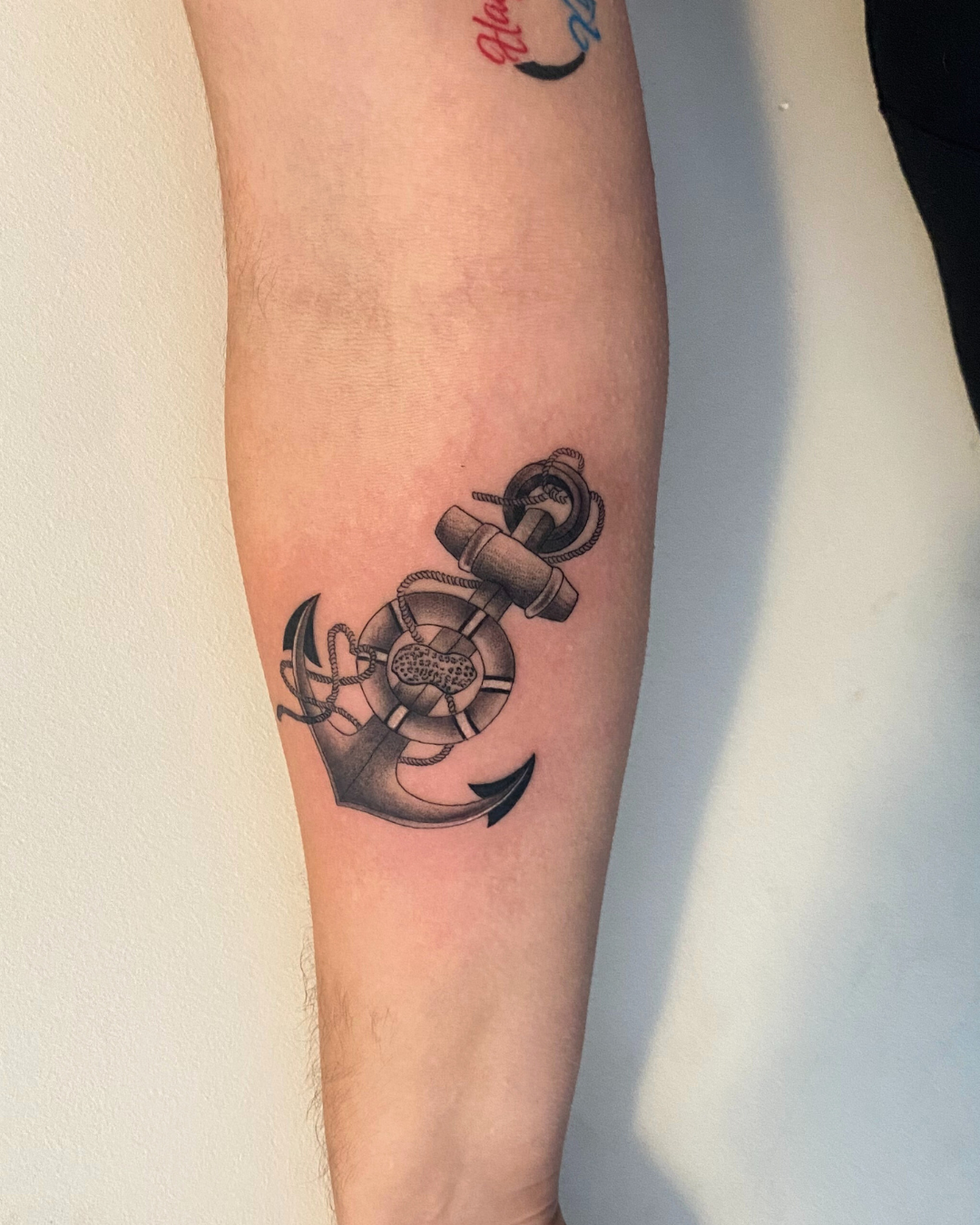 Large black and grey clock with Roman numerals and a detailed rose on the forearm