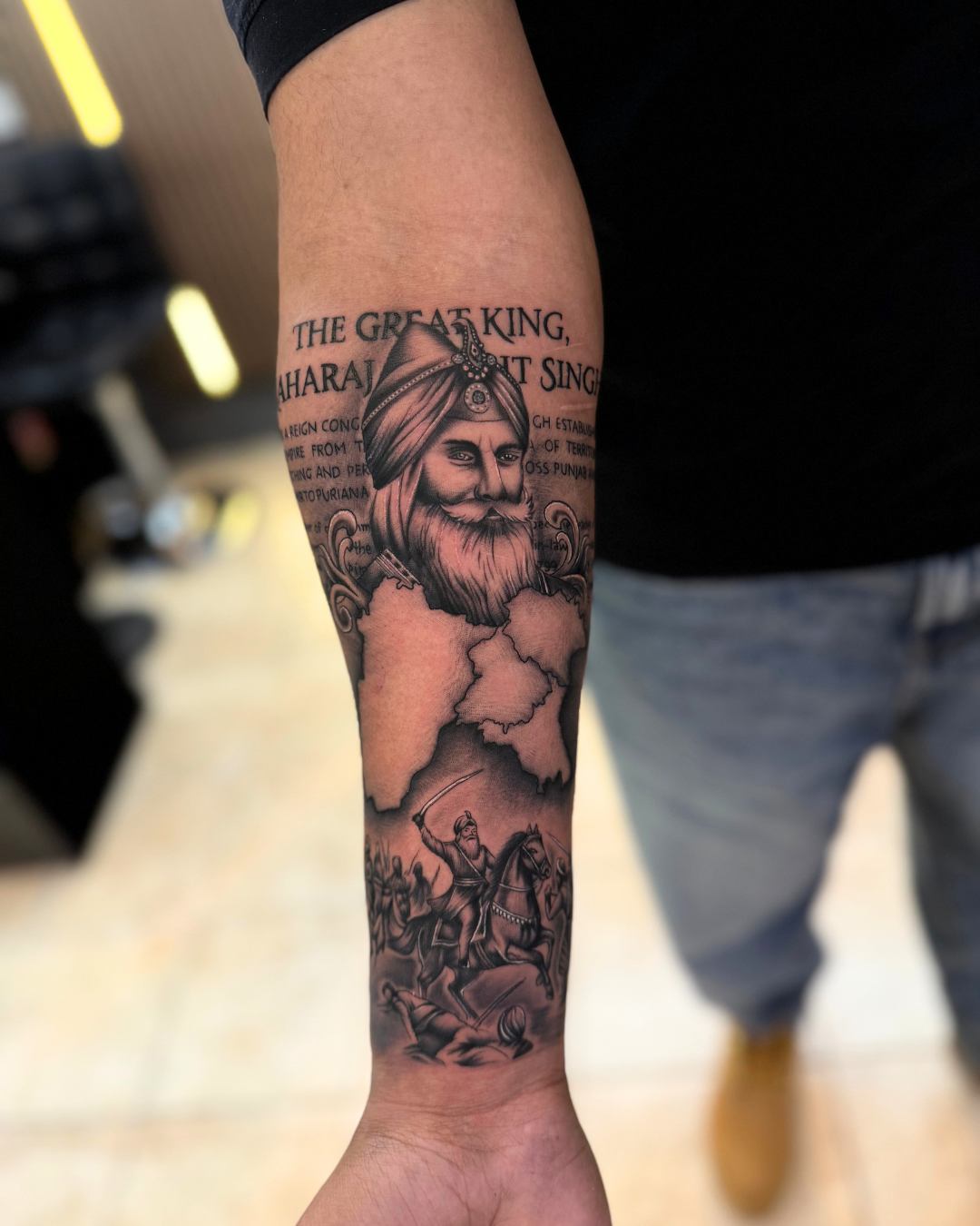 Black and grey portrait of Maharaja Ranjit Singh with Panjab map on the forearm