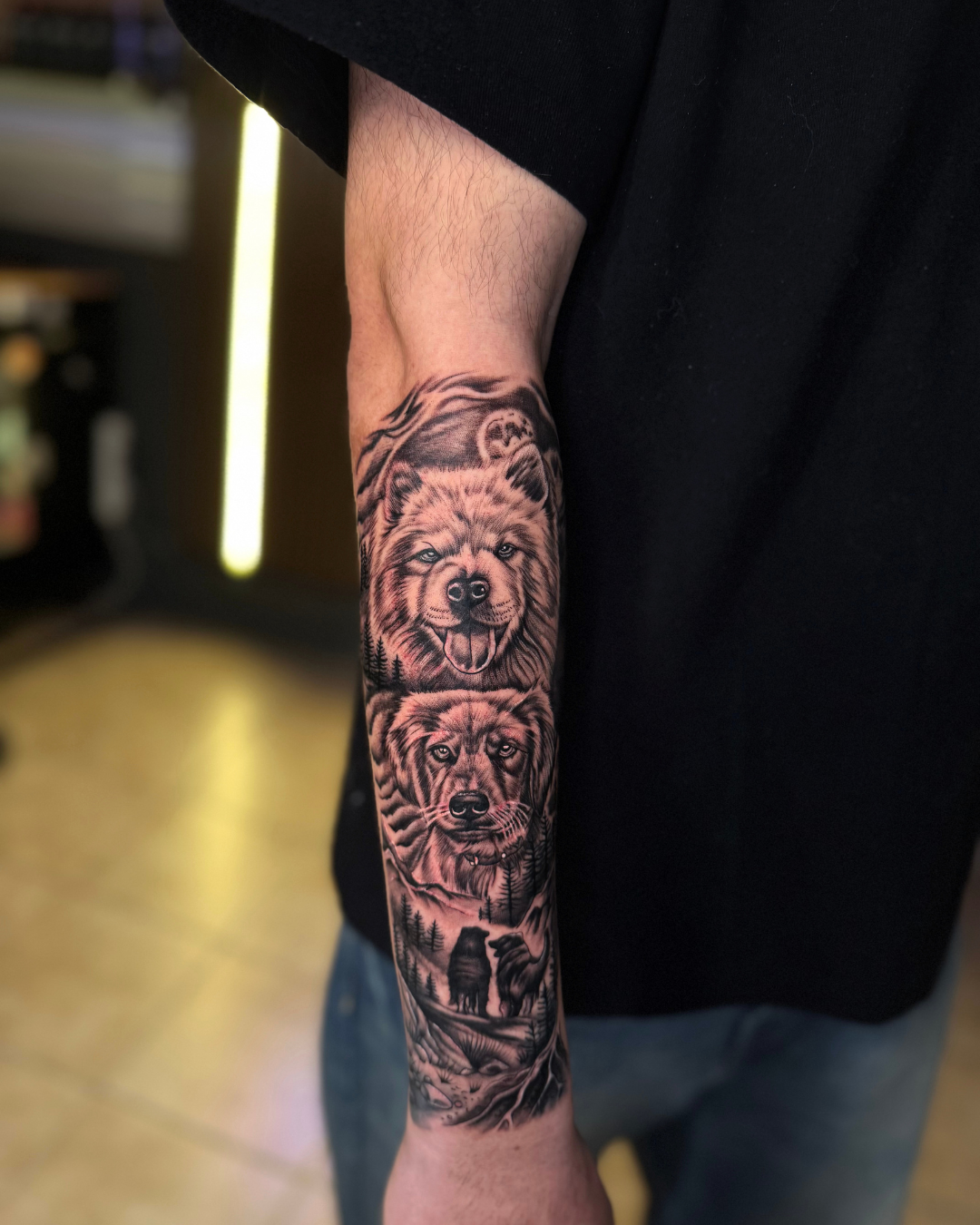 Black and grey forest scene with dog portraits and a bear on the forearm