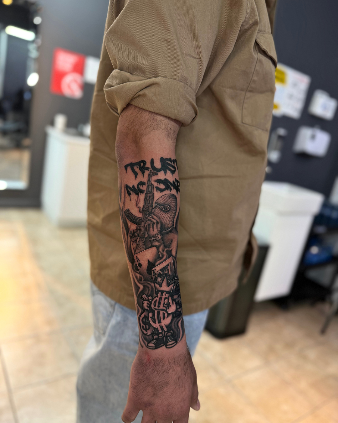 Black and grey mobster with AK-47, ski mask, playing cards, and money bag on the forearm