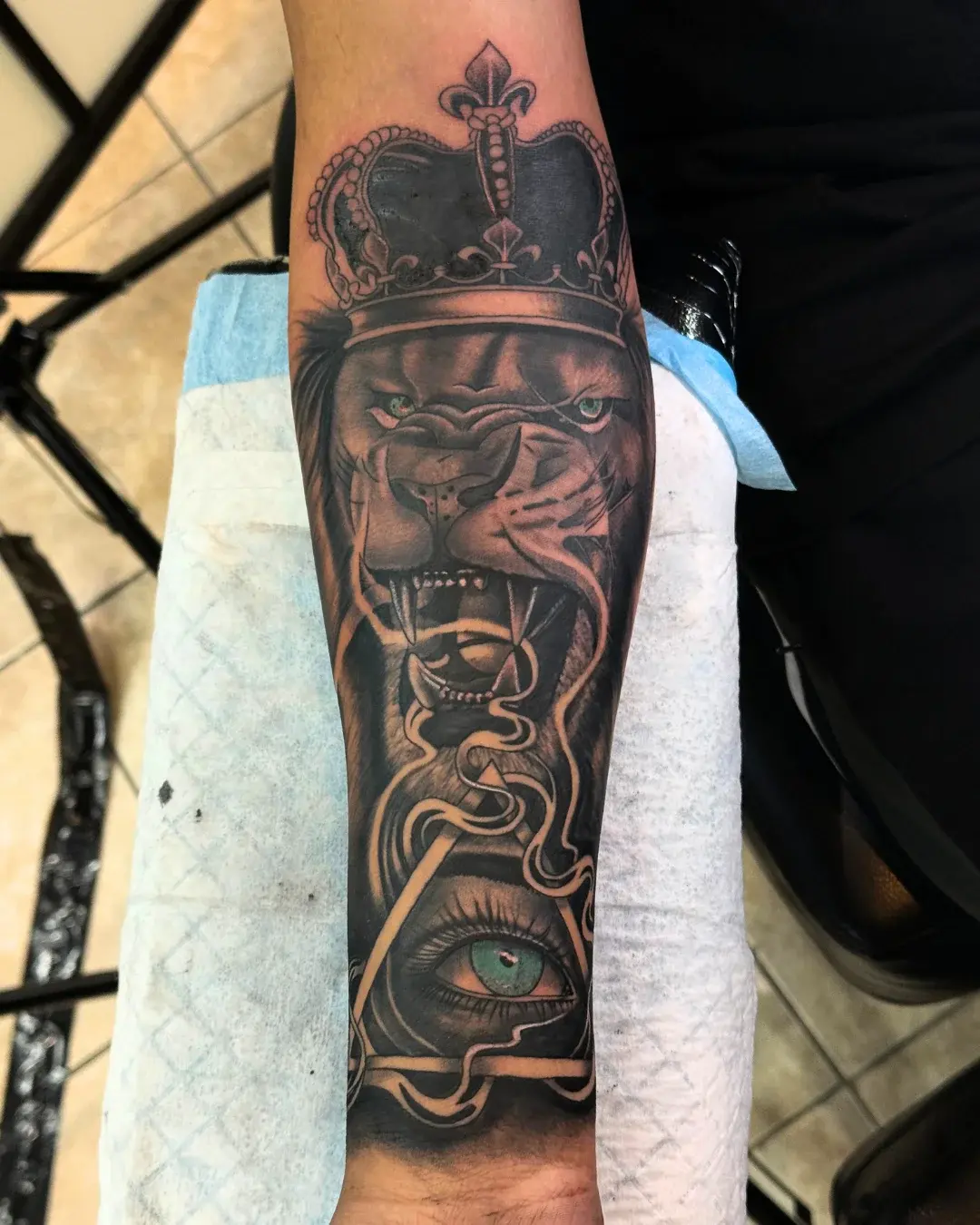 Black and grey lion with crown and eye pyramid tattoo