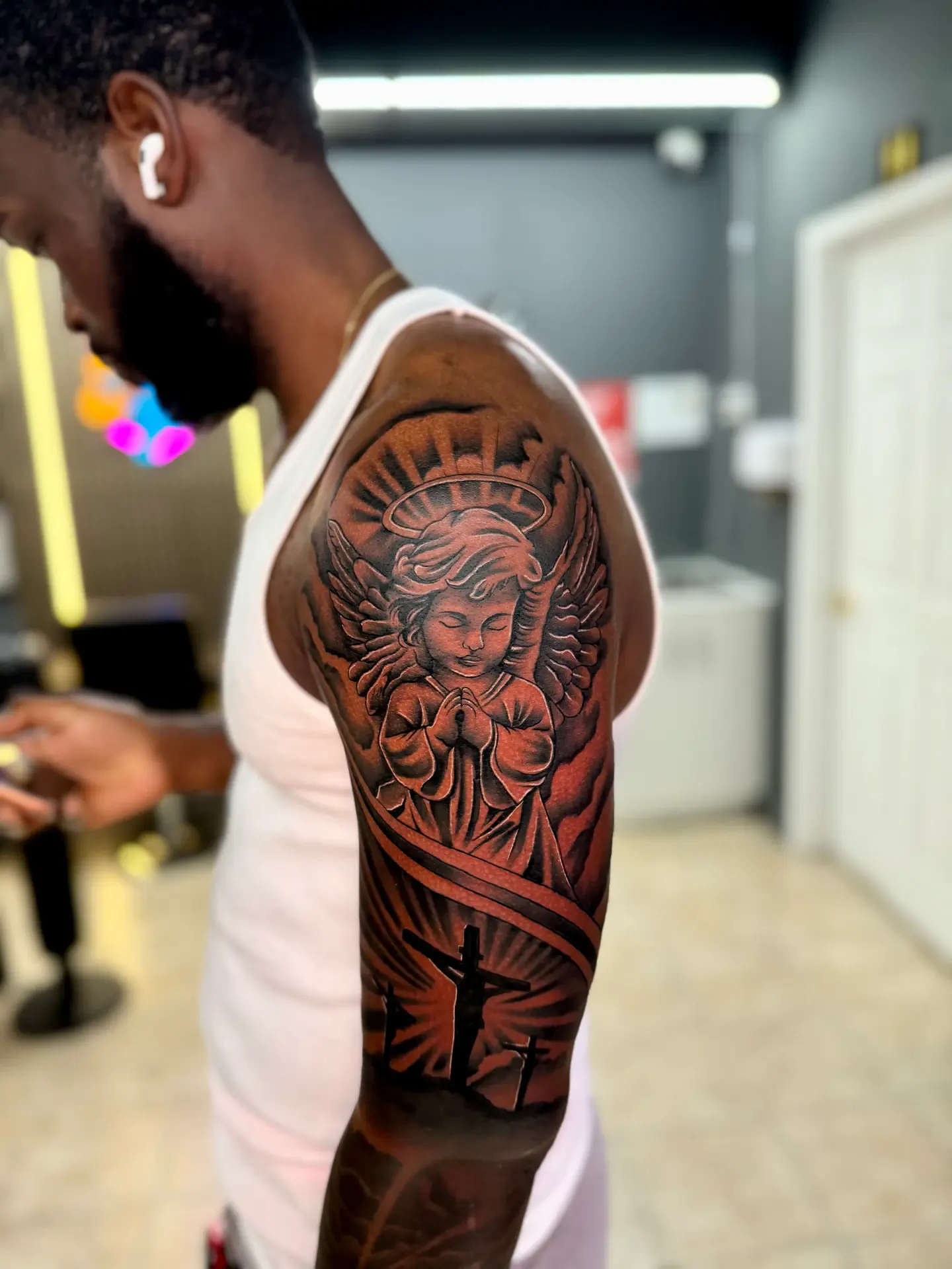 Black and grey micro-realism cherub angel with crosses on dark skin tone