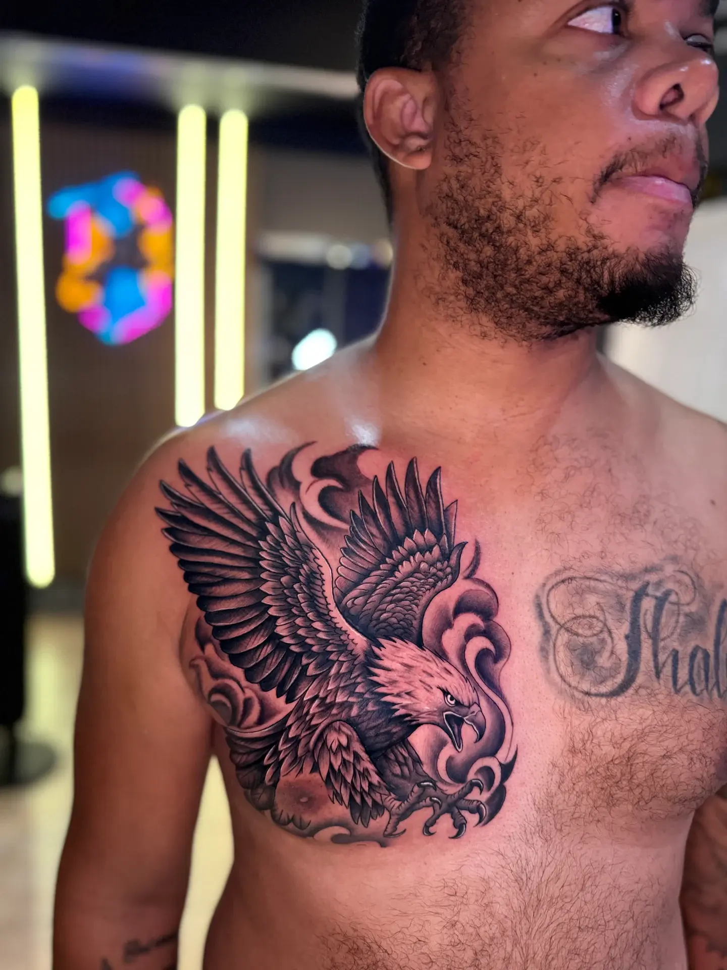 Black and grey eagle and skull chest tattoo on dark skin tone