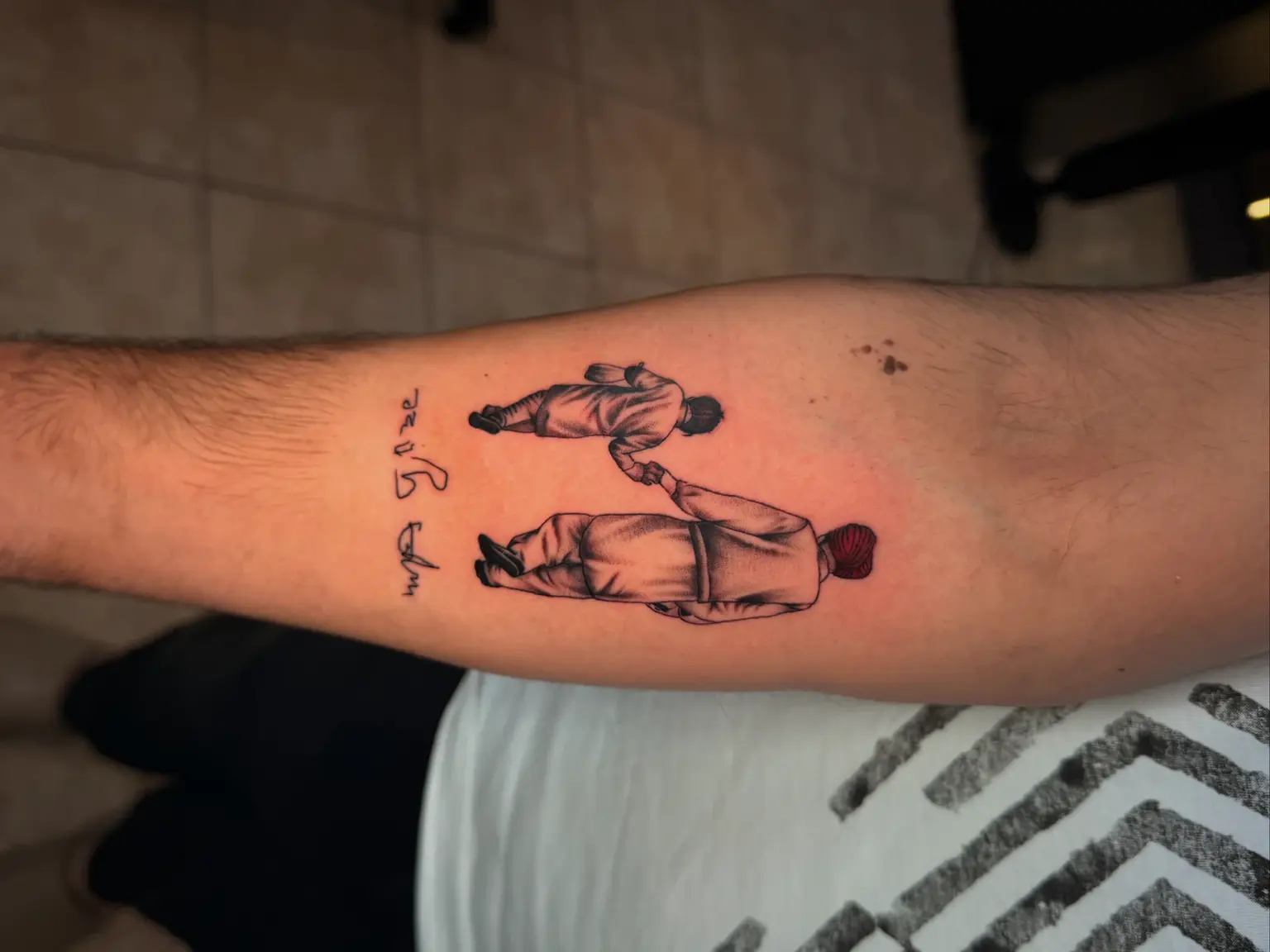 Micro-realism forearm tattoo of father holding child with red turban and custom script