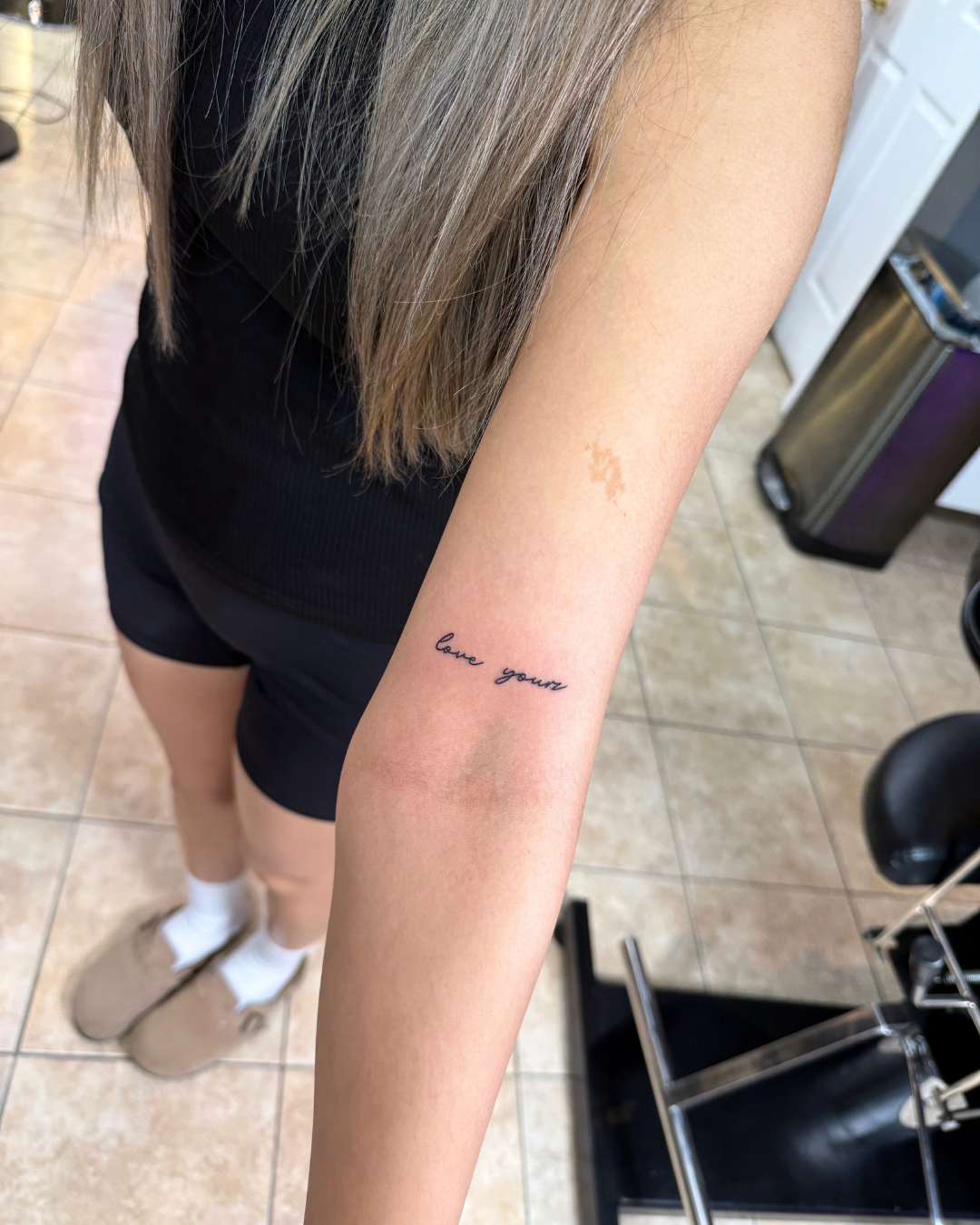 Fine line cursive script tattoo reading love yours on the forearm