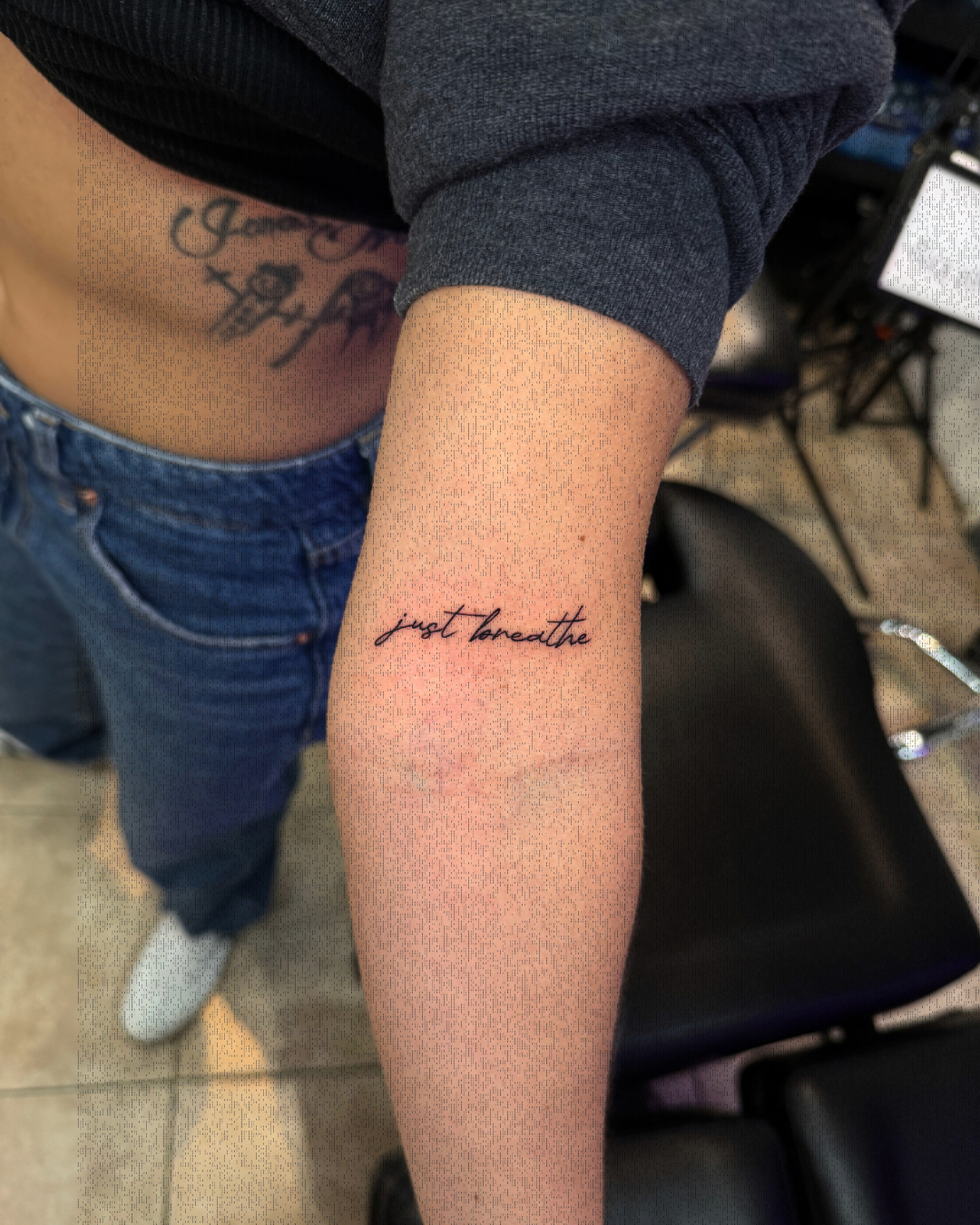 Fine line cursive script tattoo reading just breathe on the forearm