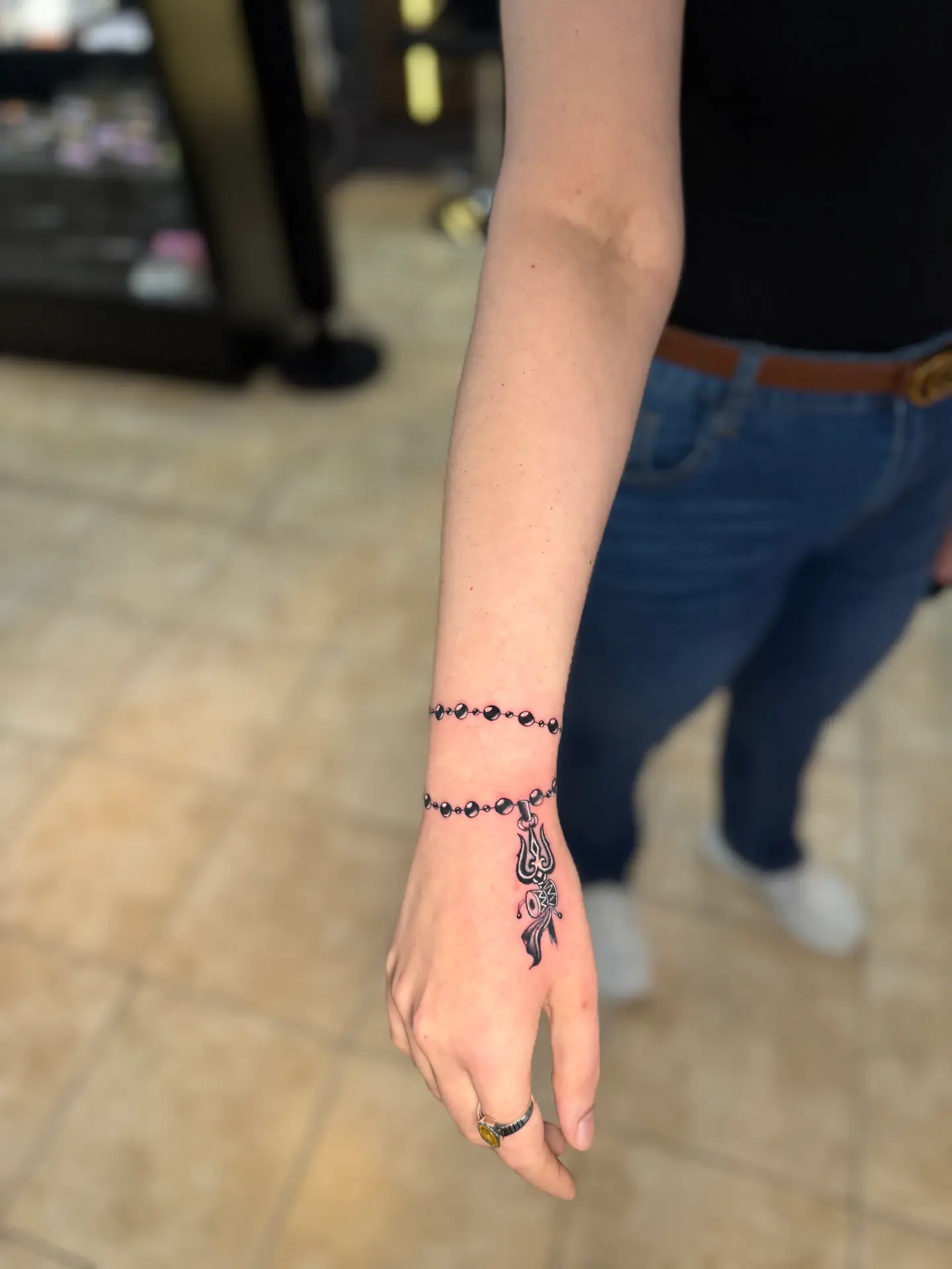Fine line 3D beaded bracelet tattoo with Trishul pendant on wrist and hand