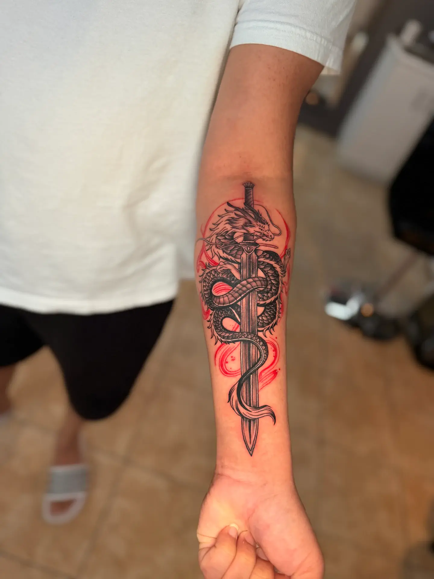 Fine line dragon wrapped around sword with subtle red accent shading