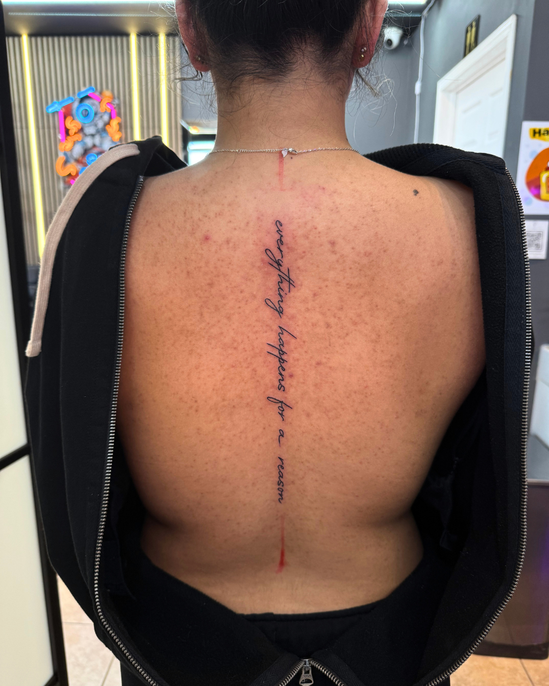 Fine line cursive script running down the spine reading everything happens for a reason