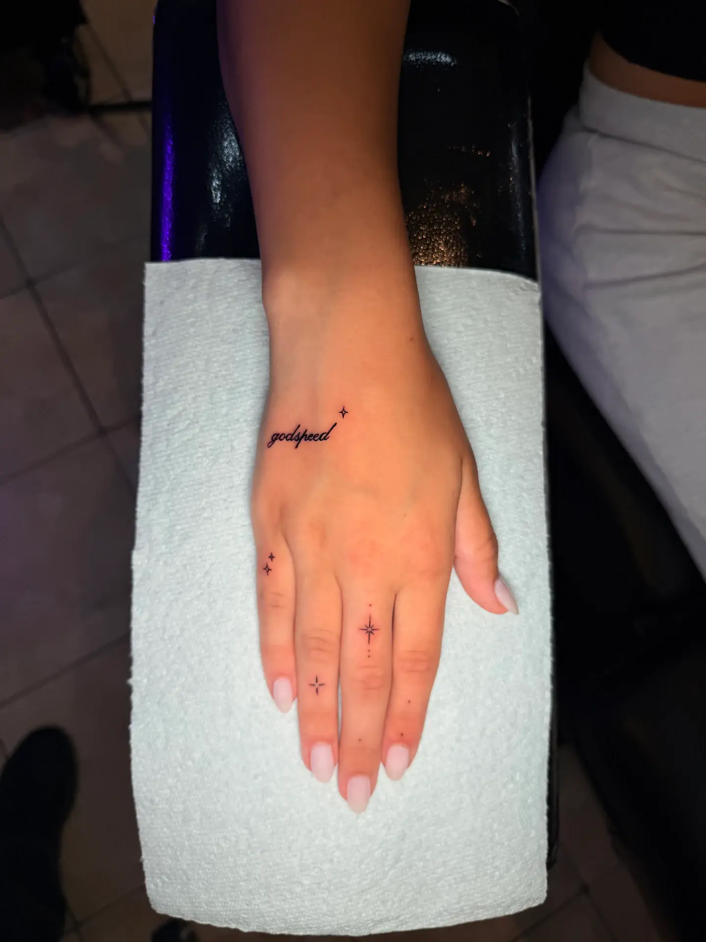 Fine line micro-script tattoo reading godspeed on hand with finger star accents