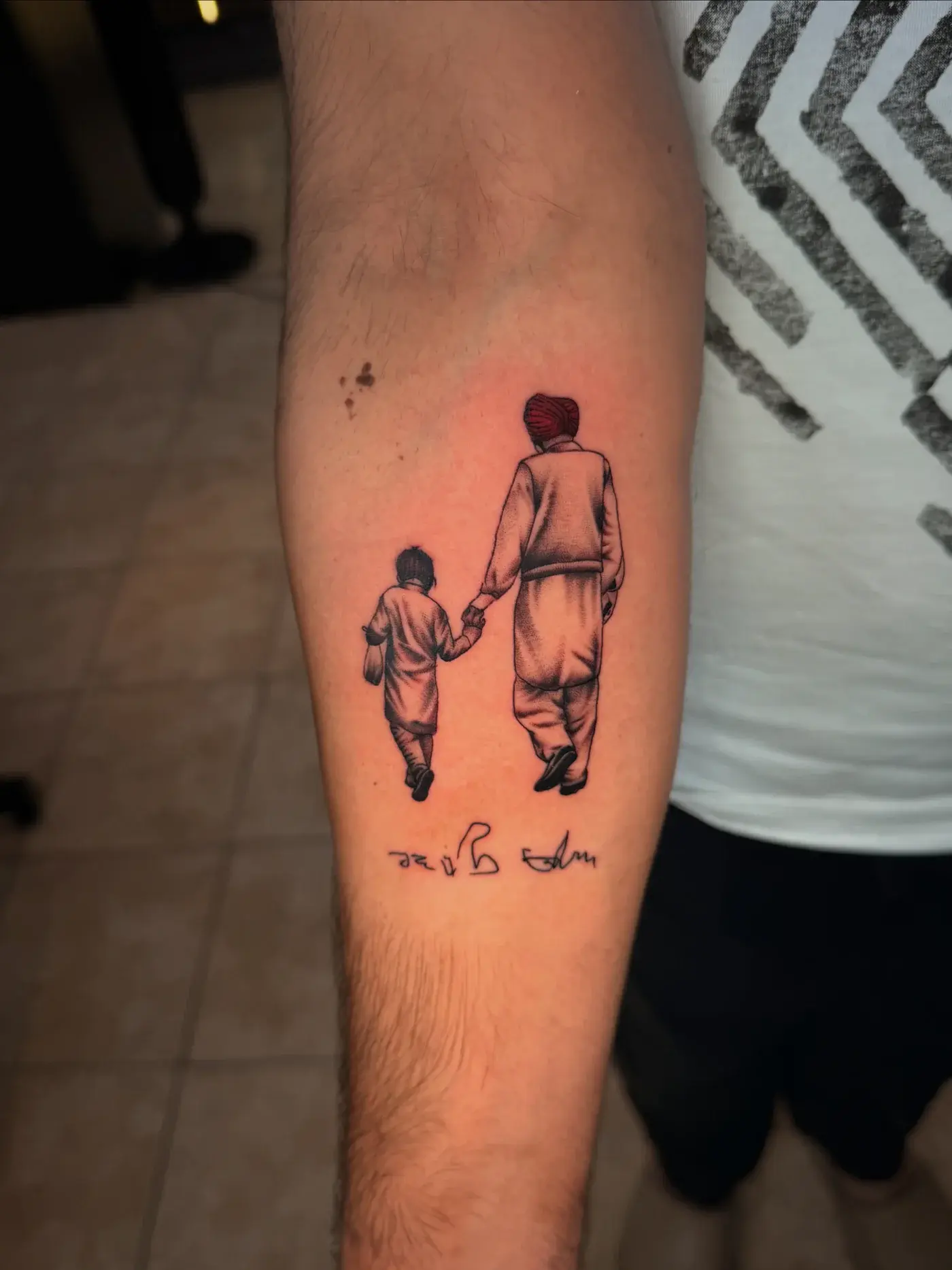Micro-realism tattoo of father walking with child with red turban pop and Gurmukhi script