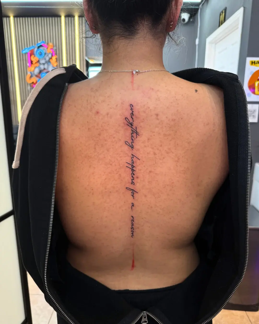 Fine line cursive script running down the spine reading everything happens for a reason